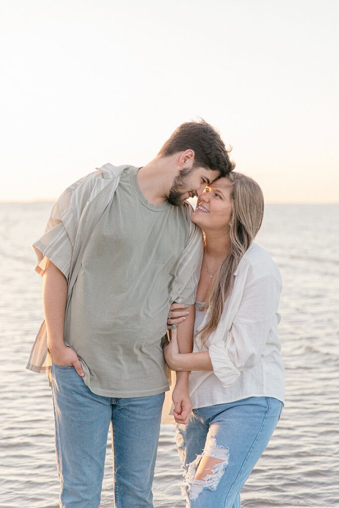 Expecting parents' embrace on the shoreline at Fish Haul Beach Park, in Hilton Head, SC, with Hilton Head Photographer, Lamp and Light Photography.