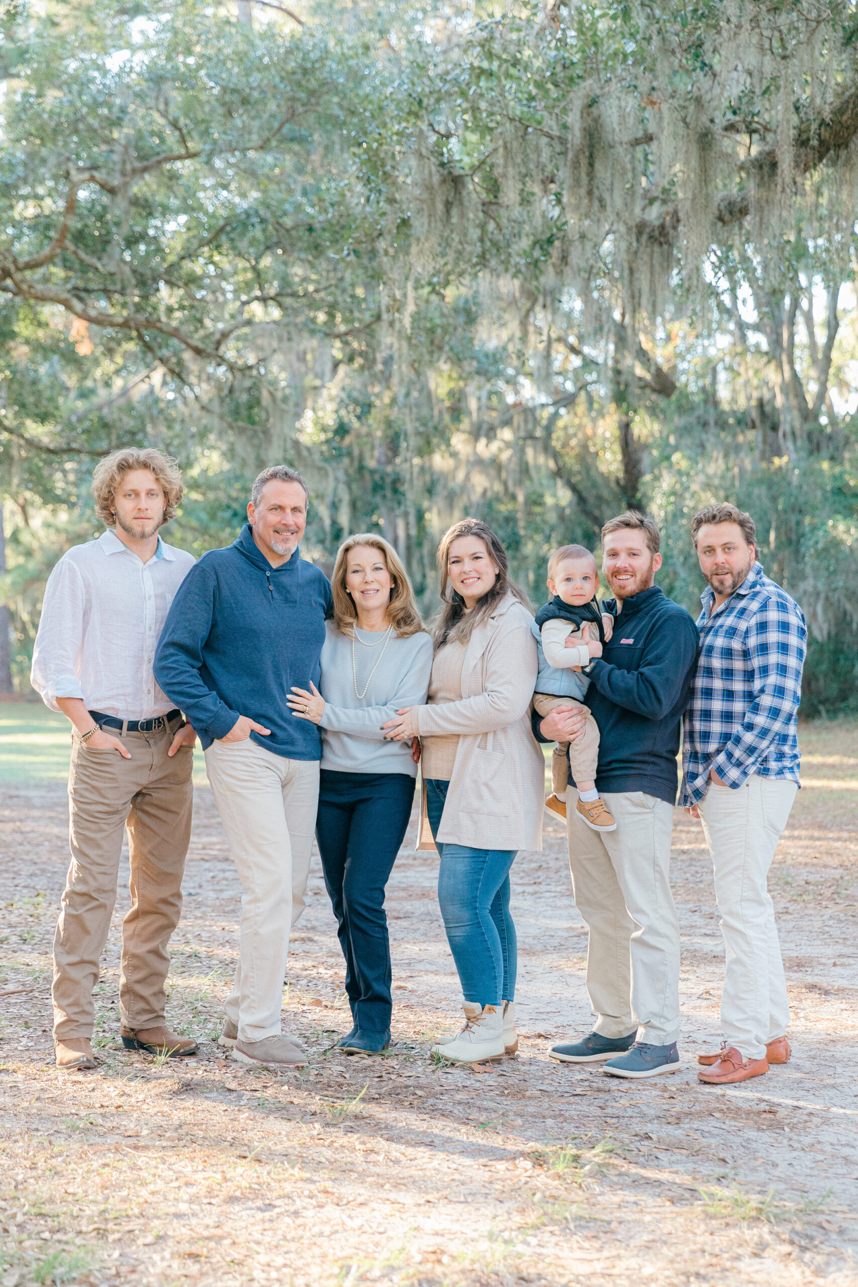 A family dressed nicely smiling together under the oak trees in Sea Pines, Hilton Head Island, SC with family photographer, Lamp and Light Photography.