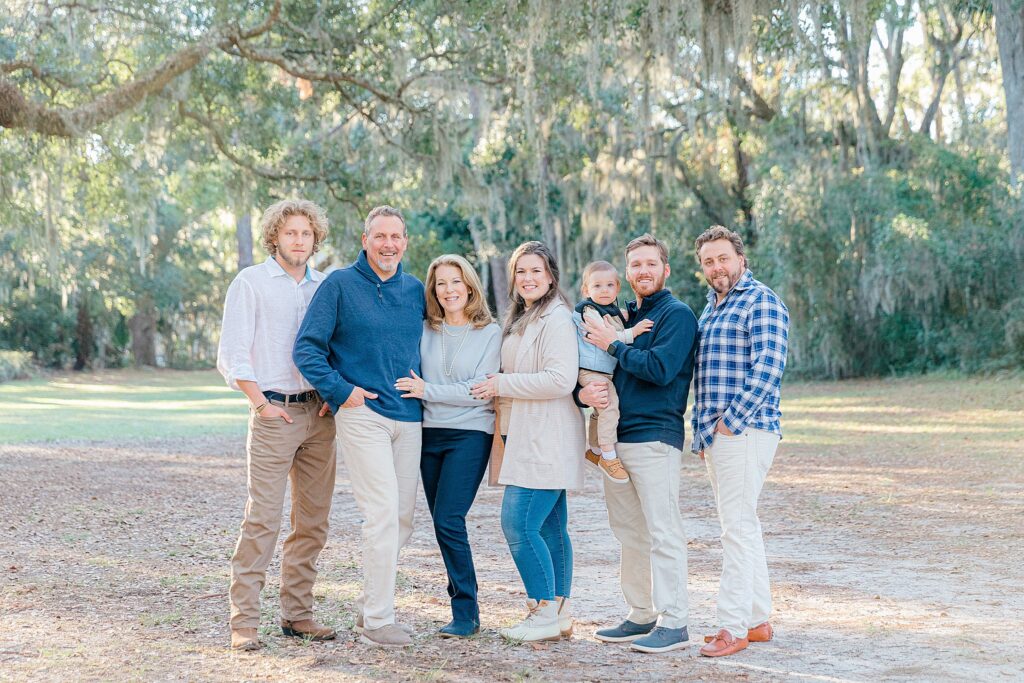 A family dressed nicely smiling together under the oak trees in Sea Pines, Hilton Head Island, SC with family photographer, Lamp and Light Photography.