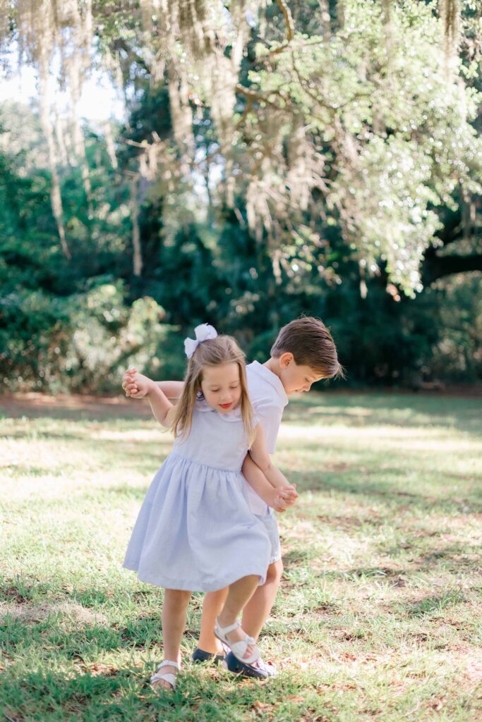 Brother and sister playing ring around the rosy backwards and being silly for their Hilton Head Family Photo Session with Lamp & Light Photography.